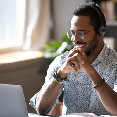 happy millennial african american man in glasses wearing headphones enjoying watching educational 1660490494